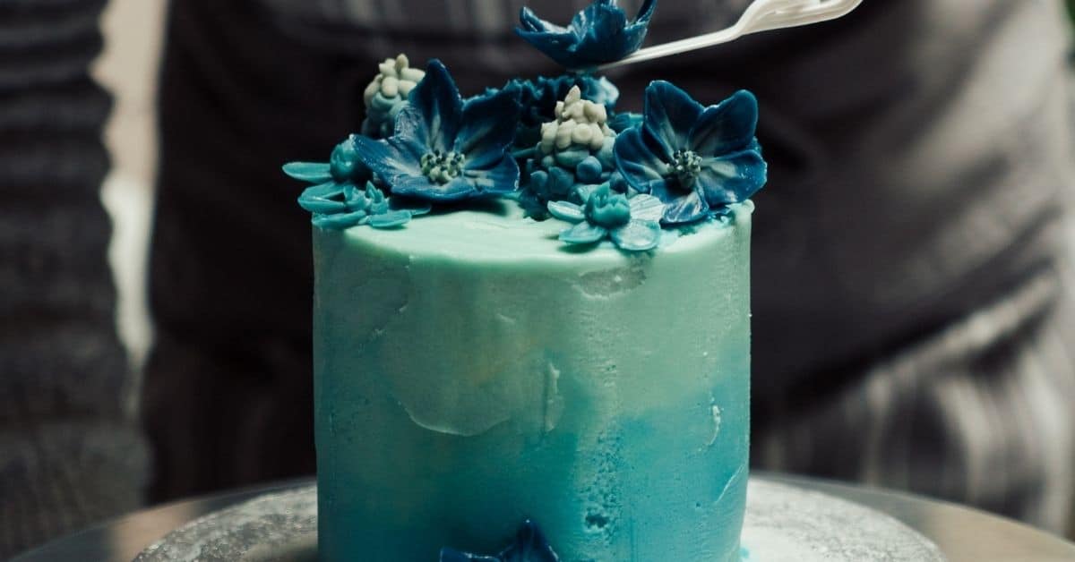 Round cake topped with flowers in shades of blue